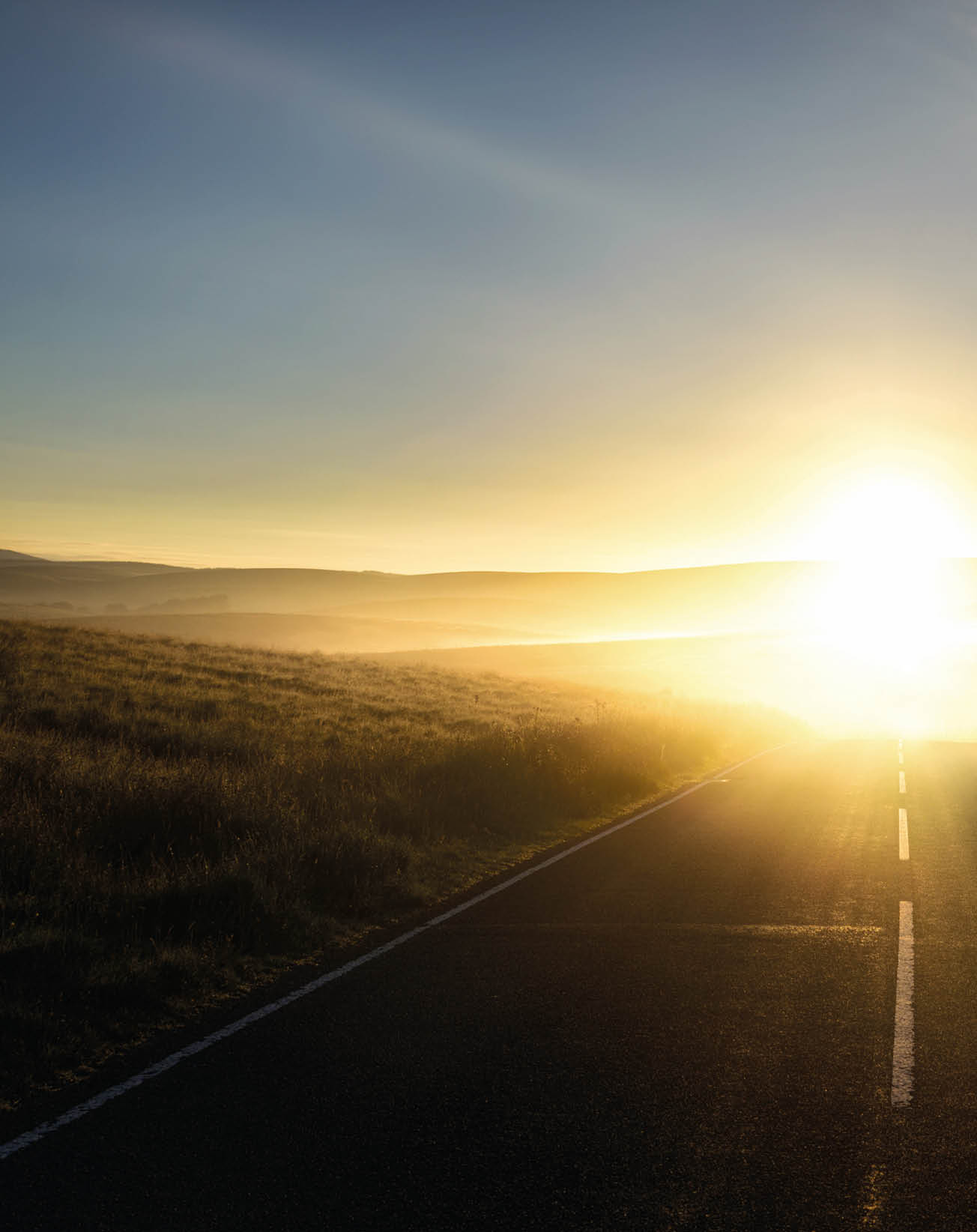 First sunlight reflecting from the mist on a road 